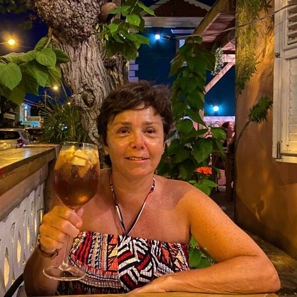 vrouw met een glas wijn zittend op een terras voor een huis op Curacao